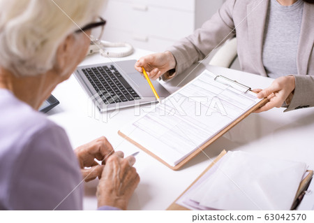 Hand of young confident insurance agent with pencil pointing at form 63042570