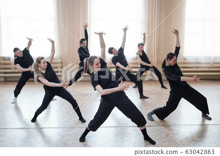 Three fit girls and four guys exercising with outstretched legs and bent knees 63042863