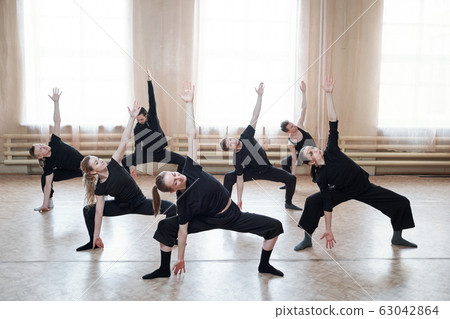 Large group of young fit people in black activewear exercising together Large group of young fit people in black activewear exercising together 63042864