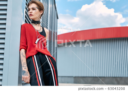 Urban Style. Young stylish woman leaning on wall outdoors pensive 63043208