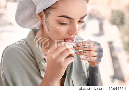 Young adult woman on balcony lick tobacco paper Young adult woman on balcony lick tobacco paper 63043214