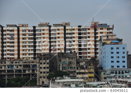 A medium-sized ship on the Shodor Gut River in Dhaka, Bangladesh A skyscraper and a building under construction along the river 63045611