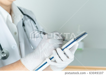 female doctor writing medical information in notebook at hospital 63049107