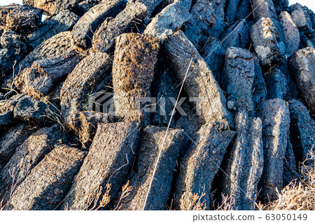 Turf fossil fuel, stacked in piles by Dunlewey in County Donegal - Ireland 63050149