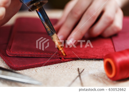 A leather craftsman works with leather. Sews A leather craftsman works with leather. Sews 63052662