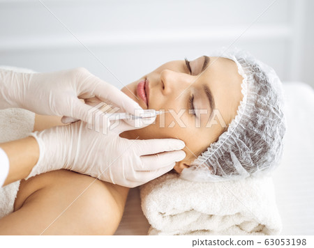Beautician doing beauty procedure with syringe to face of young brunette woman. Cosmetic medicine and surgery, beauty injections 63053198