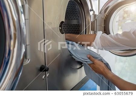 Preparing the wash cycle. Female hands getting out clean clothes. 63055679