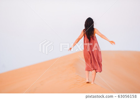 Girl among dunes in desert in United Arab Emirates Girl among dunes in desert in United Arab Emirates 63056158