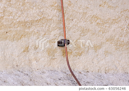 Close up image of lightning conductor on the wall. Minimalist detail of yellow building in evening light Close up image of lightning conductor on the wall. Minimalist detail of yellow building in evening light 63056246