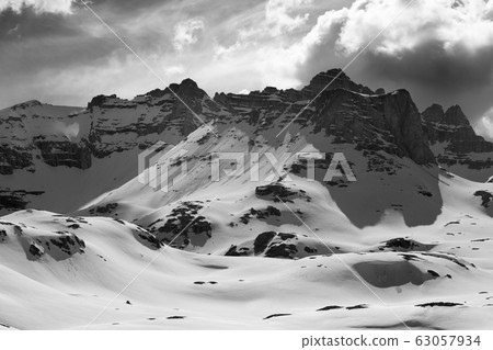 Rocks in snow and cloudy sky at winter evening 63057934