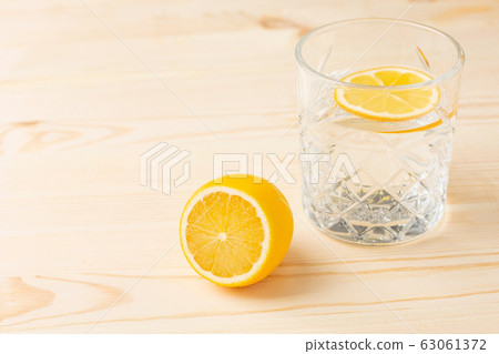 Glass of water with lemon on a wooden table, morning drink for a healthy lifestyle 63061372