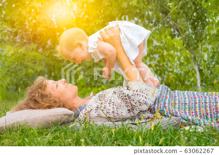 Holidays: Happy Mothers Day. Mother with child outdoor. Positive emotions of mother and toddler 63062267