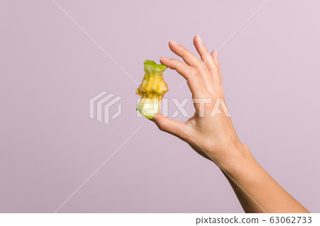 close up tender female hand gently holding an apple core over pastel pink background. healthy food concept close up tender female hand gently holding an apple core over pastel pink background. healthy food concept 63062733