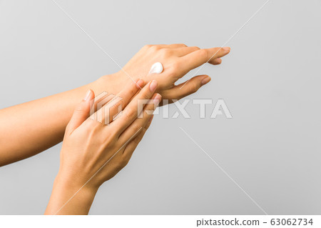closeup of tender hands of a young woman with moisturizer on. spring skin protection closeup of tender hands of a young woman with moisturizer on. spring skin protection 63062734