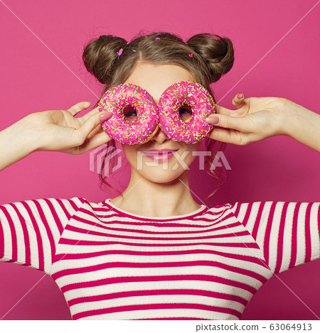 Attractive young woman showing two donuts Attractive young woman showing two donuts 63064913