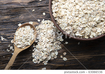 Dry oatmeal in a plate and spoon. 63066536
