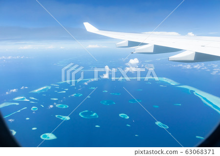 Top view of Maldive islands from airplane window with airplane's wing Top view of Maldive islands from airplane window with airplane's wing 63068371