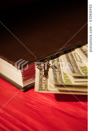 Close up money in bible book and small golden cross. Close up money in bible book and small golden cross. 63068493