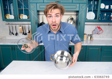 Guy with surprised face hold open saucepan, lid in Guy with surprised face hold open saucepan, lid in 63068749