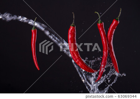 Cayenne peppers crossed with the stream of water. Cayenne peppers crossed with the stream of water. 63069344