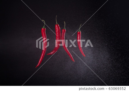 Four cayenne peppers sprayed with water. 63069352