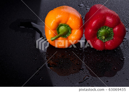 Two bulgarian peppers on wet surface. 63069435