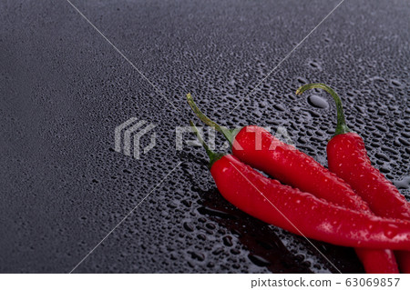 Bird peppers on wet black surface. 63069857