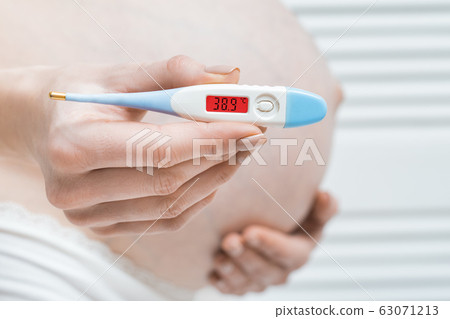 Pregnant woman with thermometer in hand and high 63071213