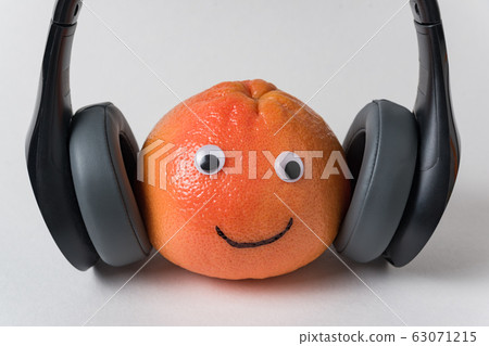 Orange with eyes and smile in headphones on white 63071215