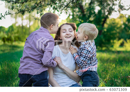Little sons kiss mom on the cheek. Happy mother Little sons kiss mom on the cheek. Happy mother 63071309
