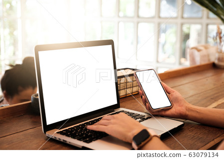 Mockup image of a businesswoman using laptop with blank white desktop screen with coffee cup on wooden table in cafe 63079134