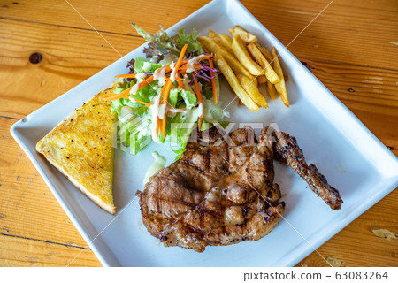 Black Pepper Pork Steak Food is popular in Asia, on a plate on a wooden floor. 63083264