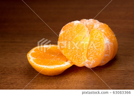 Cut tasty juicy ripe mandarin close up on a dark Cut tasty juicy ripe mandarin close up on a dark 63083366