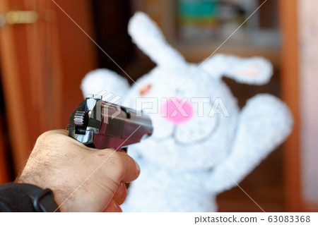 The toy rabbit is threatened with a gun. The 63083368
