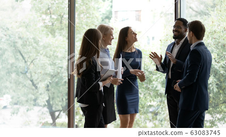Smiling diverse colleagues have fun talking in office Smiling diverse colleagues have fun talking in office 63083745