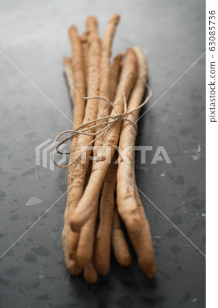 bunch of handmade wholegrain grissini tied with rope on concrete surface bunch of handmade wholegrain grissini tied with rope on concrete surface 63085736