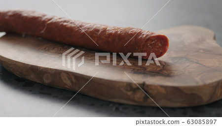 chorizo sausage on olive wood board closeup 63085897