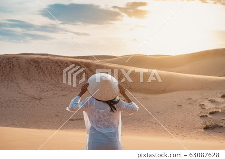 Young woman traveler looking sunset at red sand 63087628