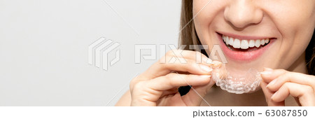 Young woman holding invisible aligner Young woman holding invisible aligner 63087850