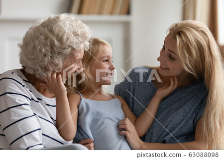 Overjoyed three generations of women relax at home 63088098