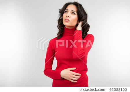 pensive brunette in a red turtleneck on a white studio background 63088100