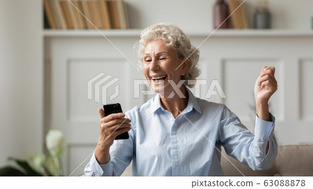 Overjoyed mature woman triumph reading good news on cell Overjoyed mature woman triumph reading good news on cell 63088878
