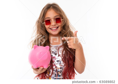 Pretty girl smiles and holds her moneybox, picture isolated on white background 63089802