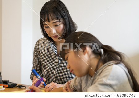 Mother watching over child writing on paper about decisions made at family disaster prevention meeting Mother watching over child writing on paper about decisions made at family disaster prevention meeting 63090745
