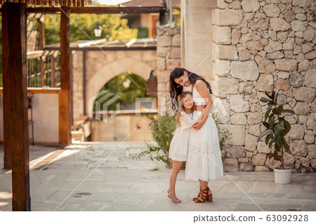 Young beautiful mother of eastern appearance walks with her daughter on the ancient streets of the Mediterranean city Young beautiful mother of eastern appearance walks with her daughter on the ancient streets of the Mediterranean city 63092928