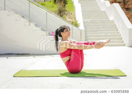 A woman in the open air dressed in sportswear warms up and exercises A woman in the open air dressed in sportswear warms up and exercises 63095898