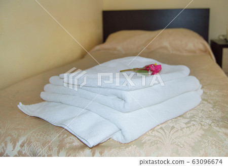 Interior of the hotel with a bed covered with a luxurious gold bedspread and a set of white towels with a flower 63096674