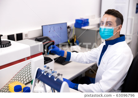 Handsome male researcher sitting at the table in science laboratory Handsome male researcher sitting at the table in science laboratory 63096796