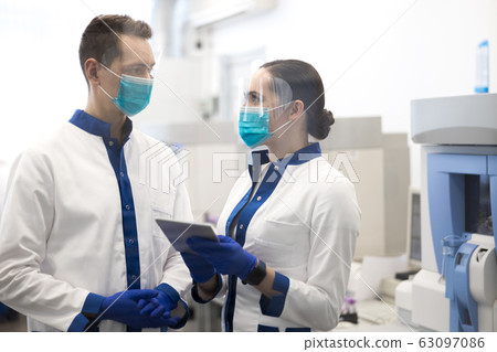 Scientists in medical masks discussing research in laboratory Scientists in medical masks discussing research in laboratory 63097086