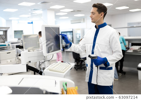 Young male scientist using lab machine for pathology blood test Young male scientist using lab machine for pathology blood test 63097214